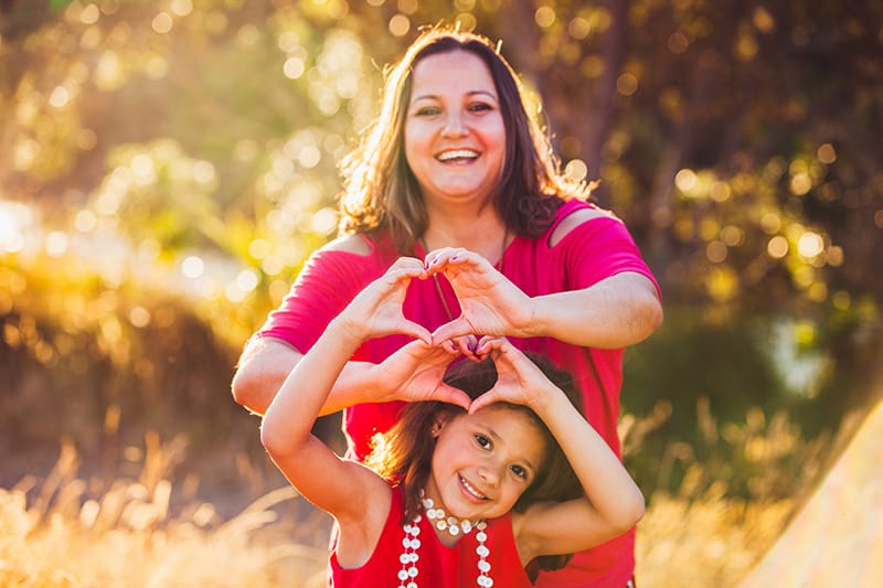 mom and daughter holding up heart hands