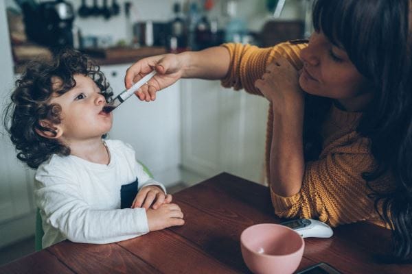 child getting medication from his mother