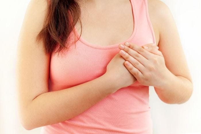 women in pink tank top holding hands over left chest