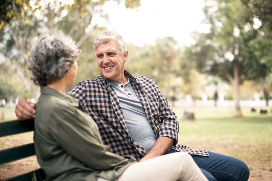 middle aged couple talking on park bench