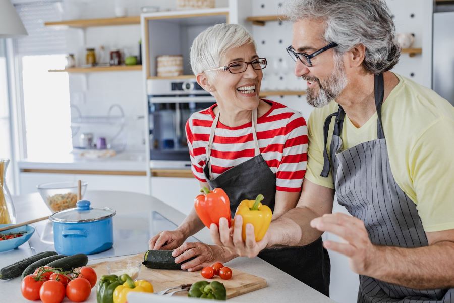middle aged couple prepping vegetables in kitchen together