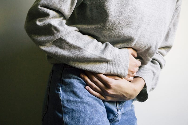 woman hunched over clutching stomach in pain
