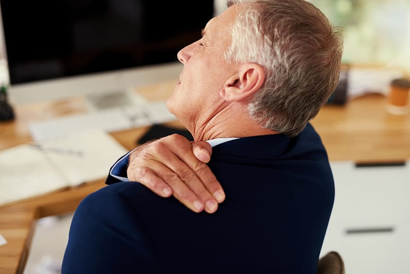 man in pain rubbing shoulder