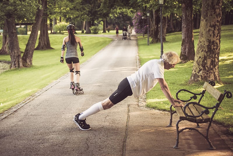 man doing push ups on park bench