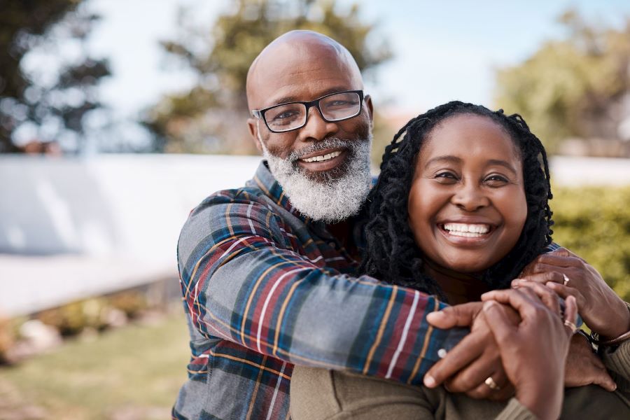 man with arms around wife smiling at the camera