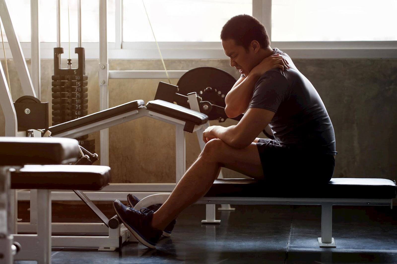 man on rowing machine in pain rubbing shoulder