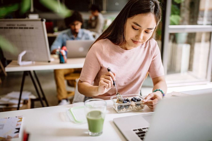 young woman having healthy lunch at work desk