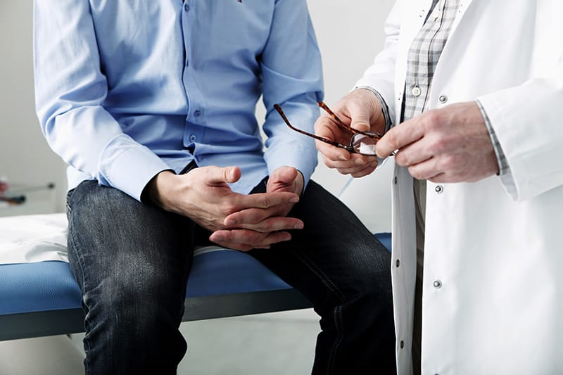 man sitting on doctor table next to doctor