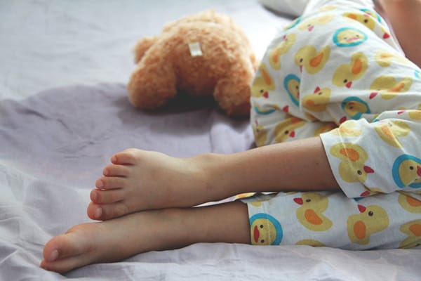 child laying next to a wet bed