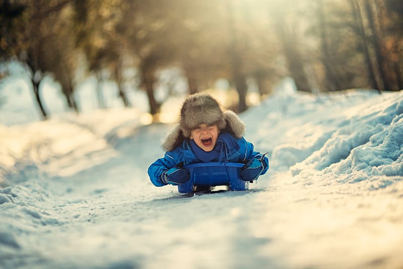 kid sledding down hill in the winter time