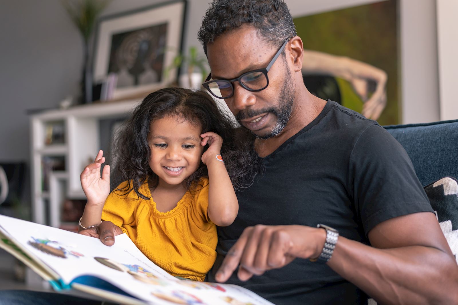man looking a book with his daughter