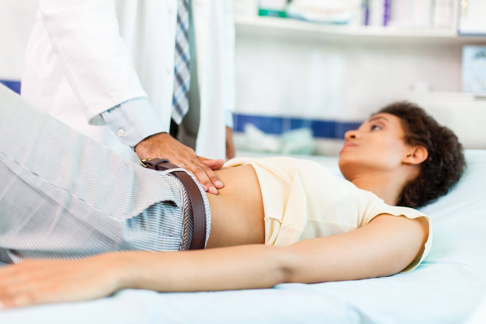 woman lying down with doctor pushing on her abdomen