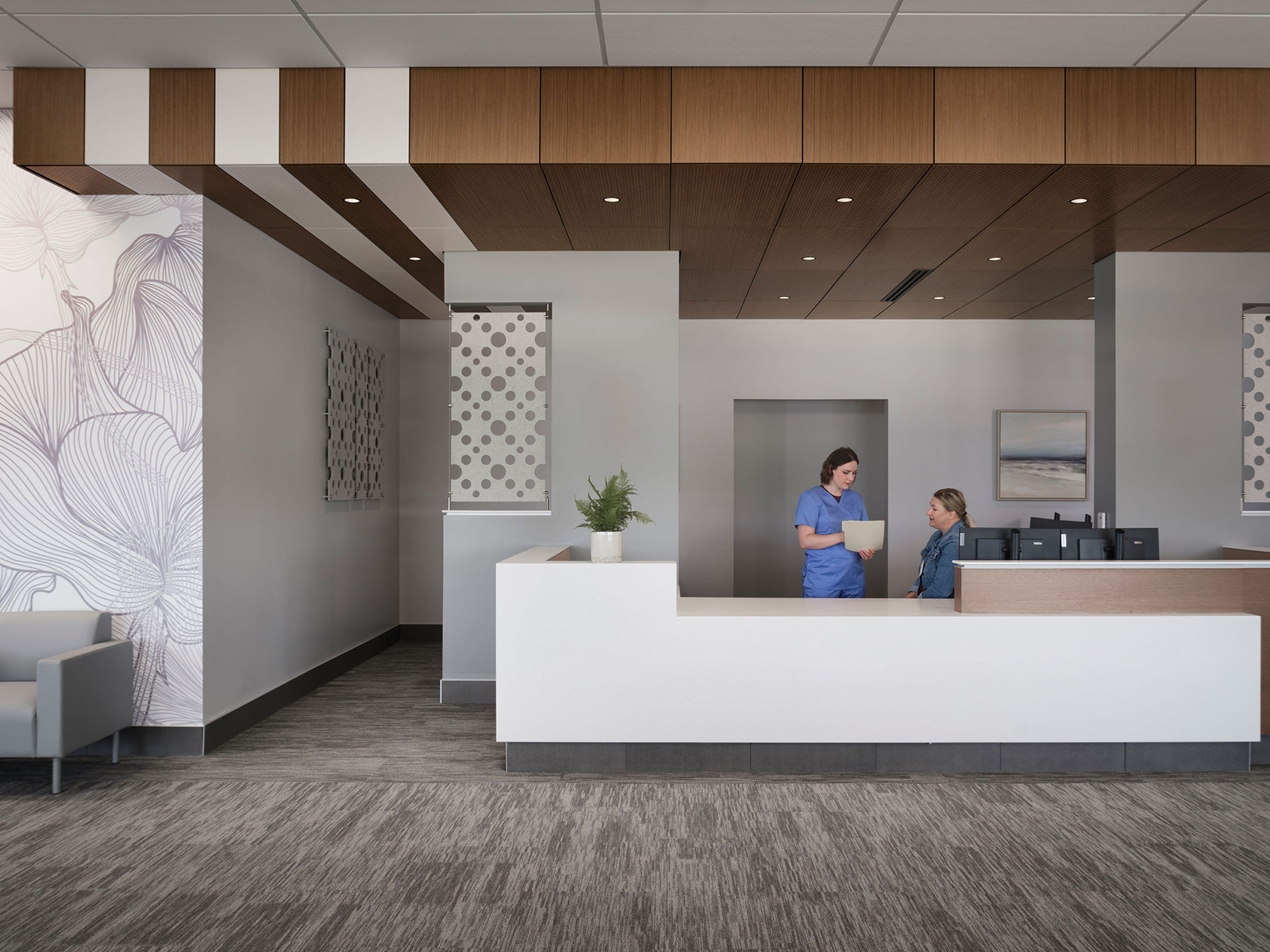 two nurses converse behind check-in desk