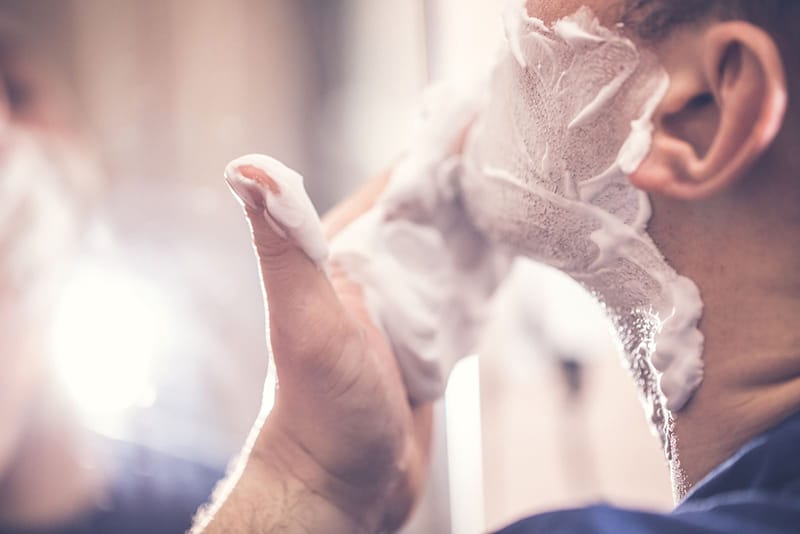 man putting shaving cream on his face