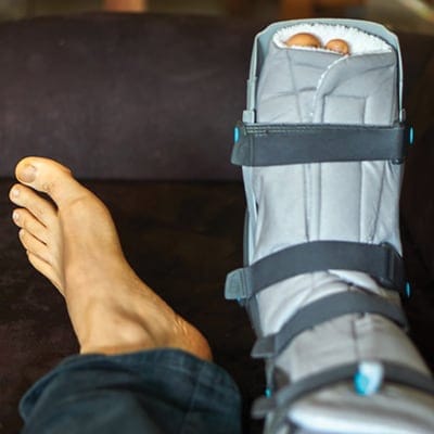 feet on a couch with a foot in a boot