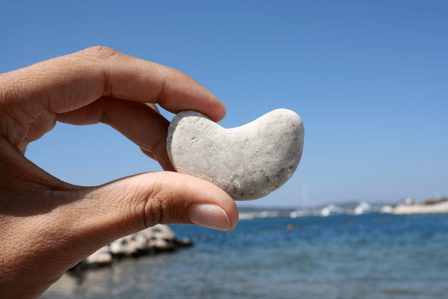 a person holds a stone near a body of water
