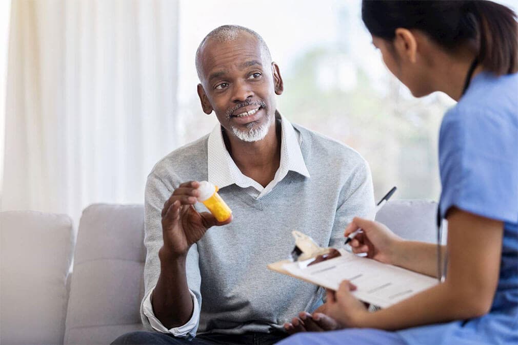 man talks to doctor while holding pills