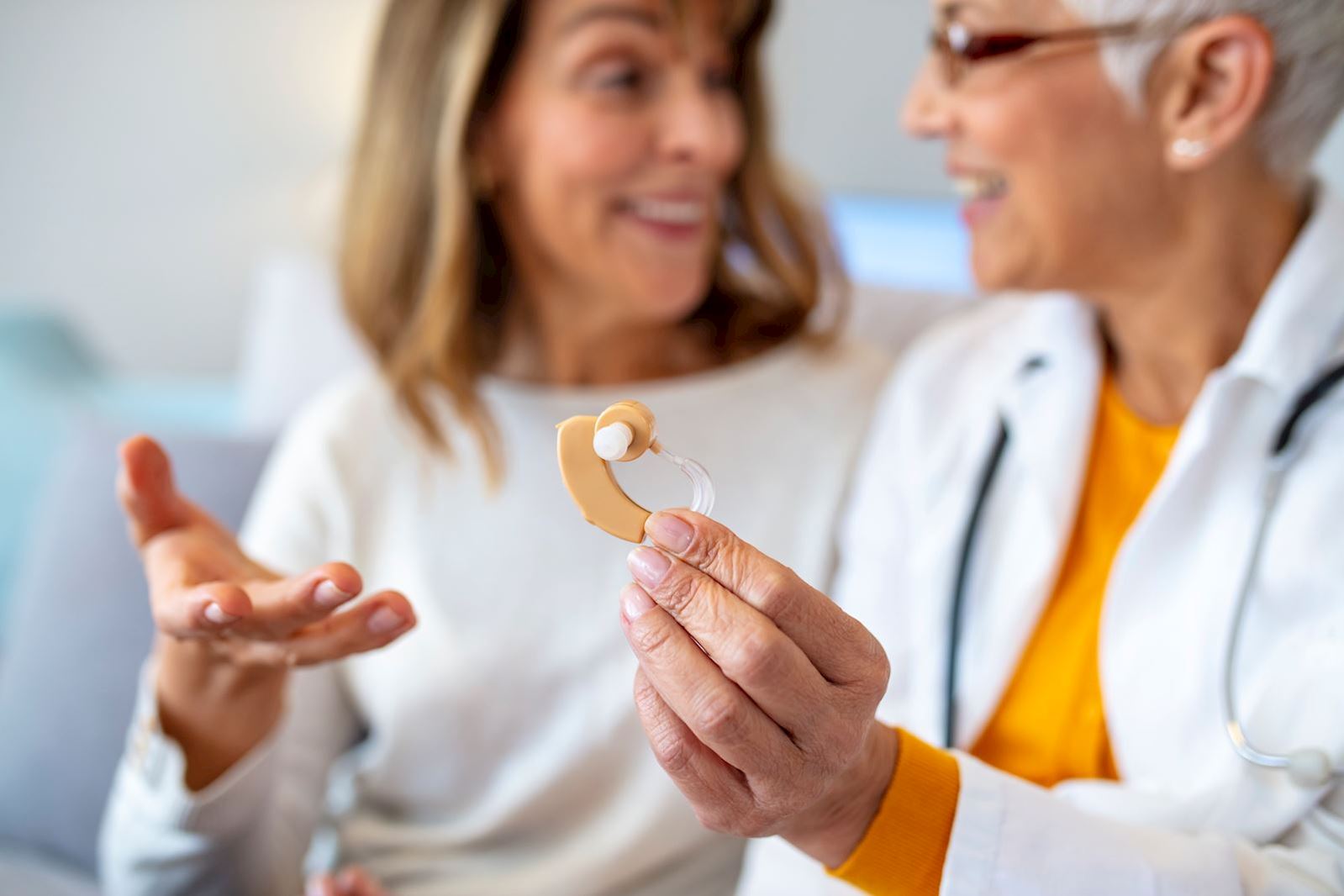 doctor shows patient a hearing aid
