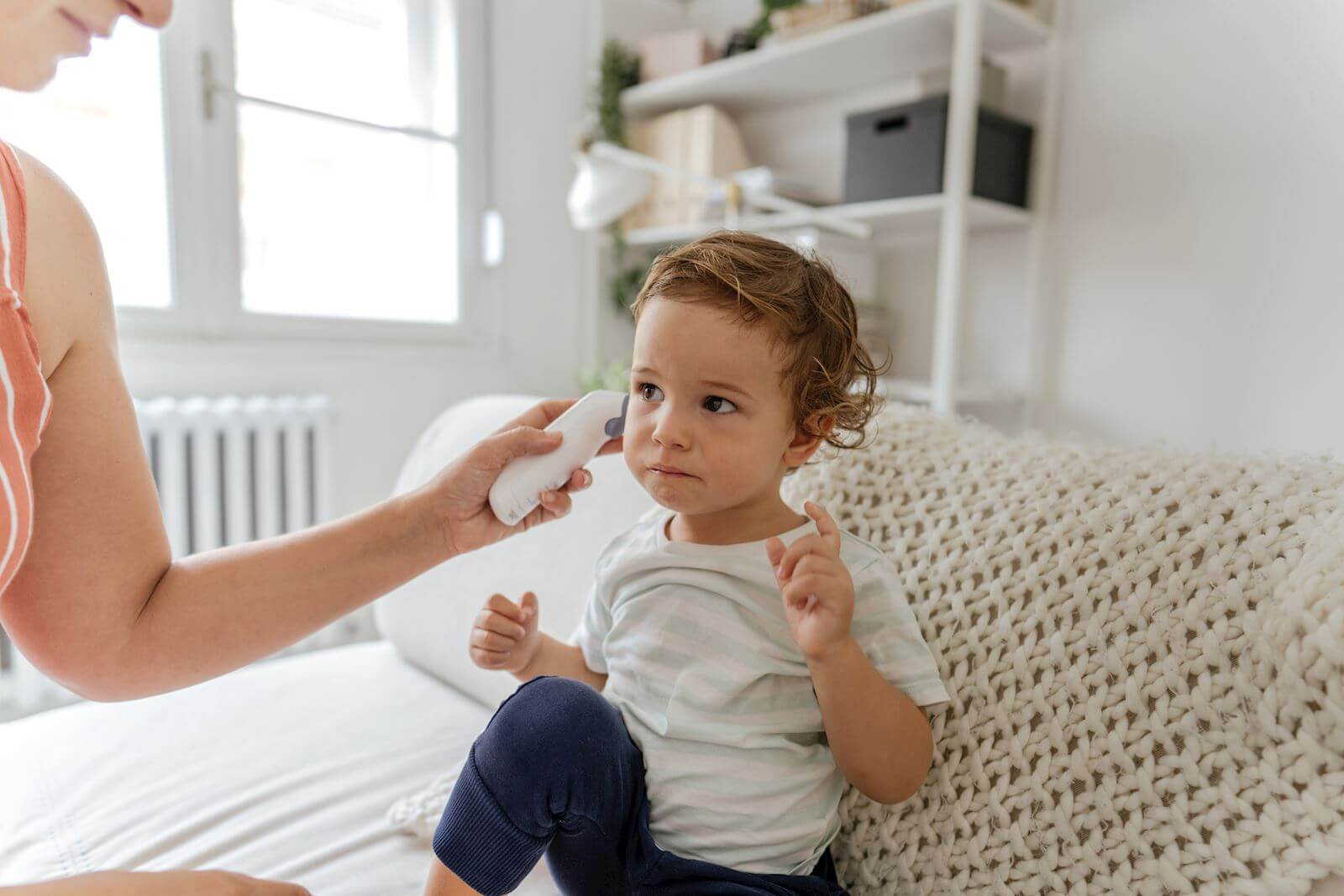 parent checks child's ear temperature using thermometer