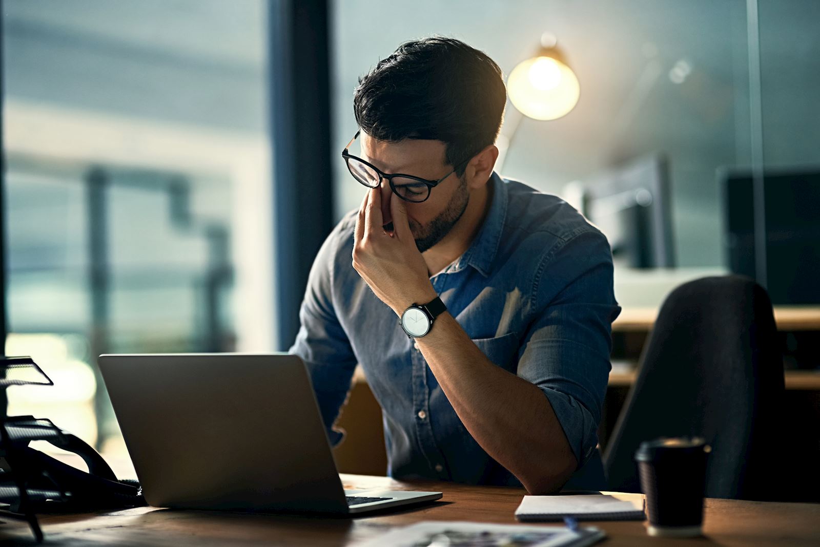 man at desk, pinching nasal bridge