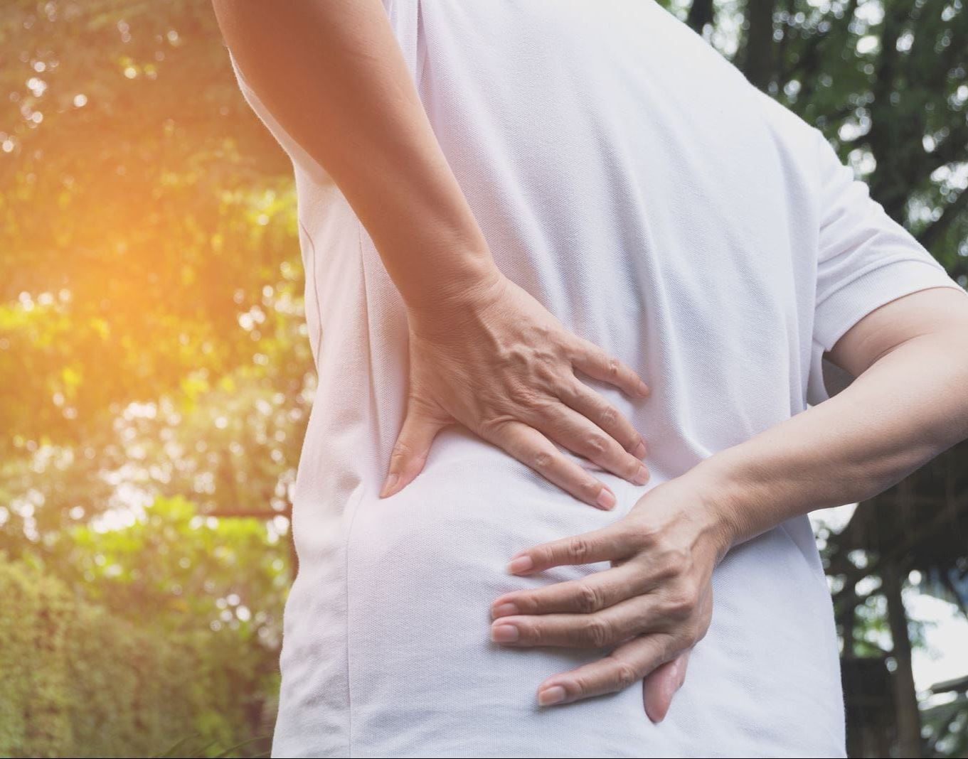 man outdoors grasping back
