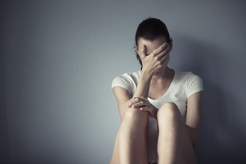 woman sitting on floor with head in hand