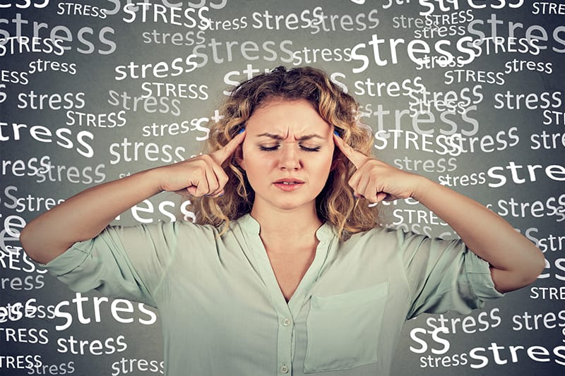 woman touching temples, surrounded by the word stress