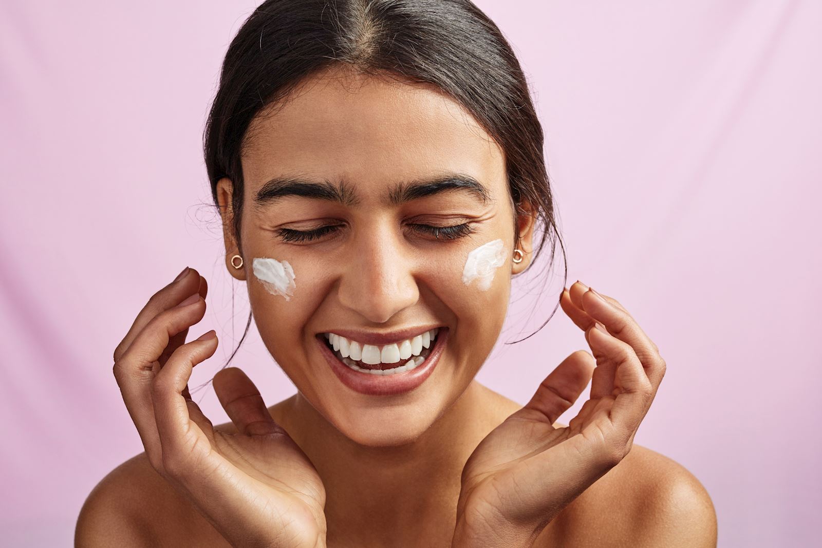 woman happily applying a product to her face