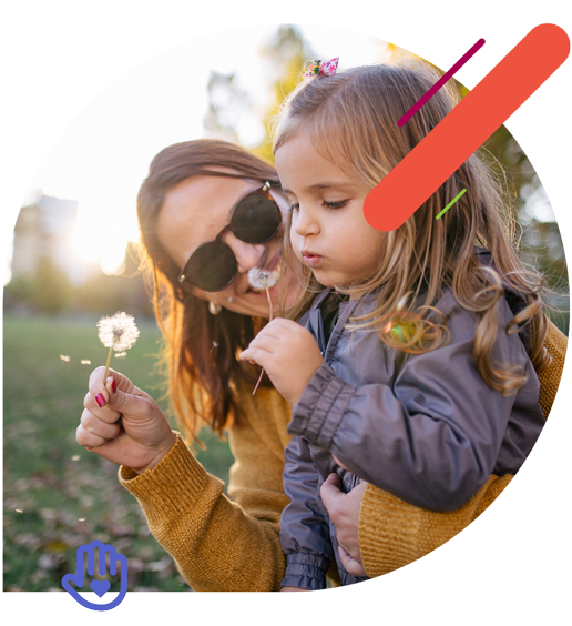 Mother and toddler daughter blowing out dandelions