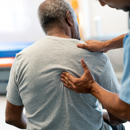 Doctor checking a patients back near their shoulder blade