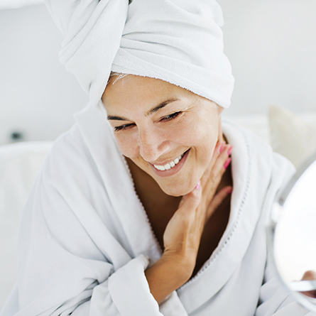 woman looks at skin in mirror