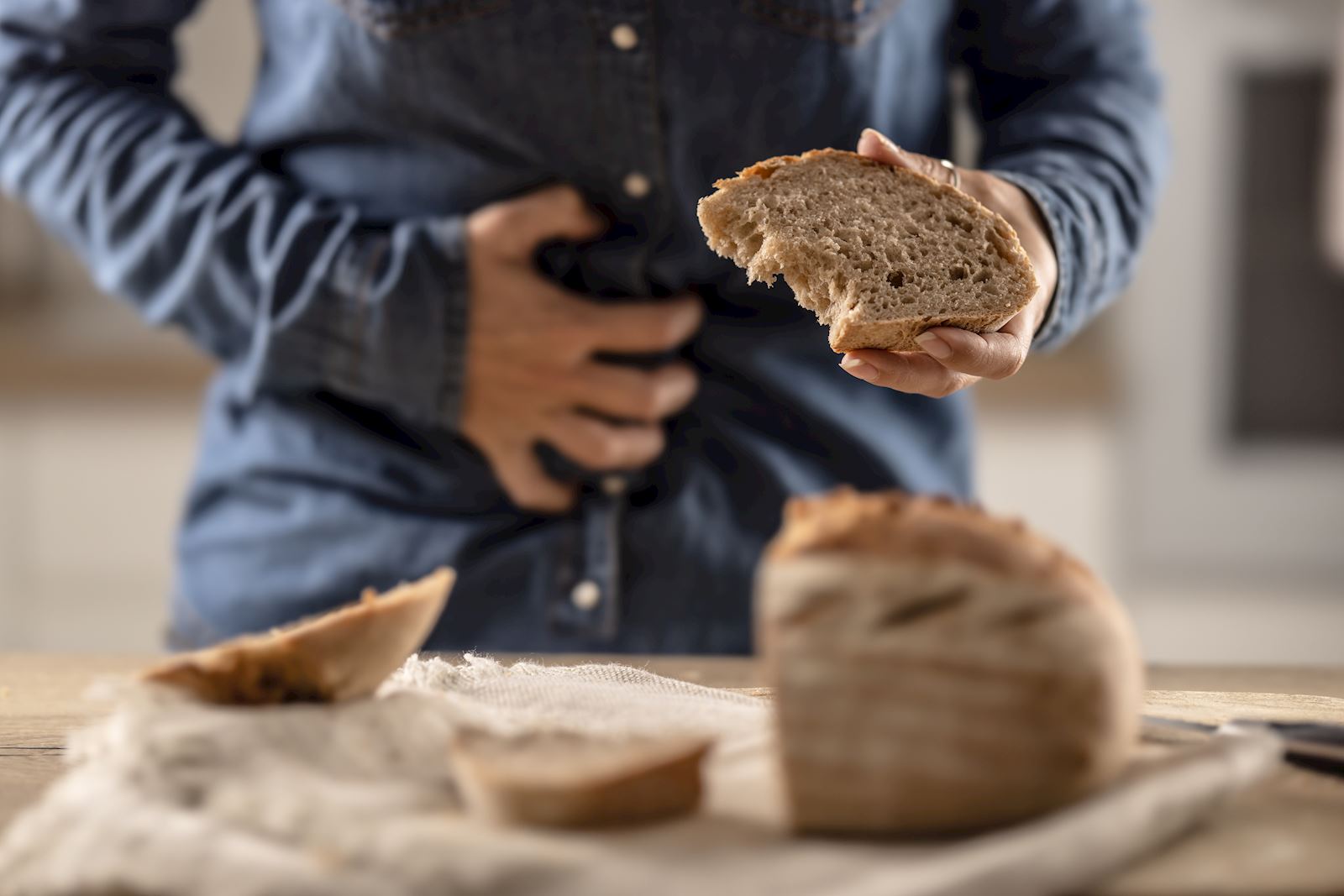 person holding bread while clutching stomach in pain