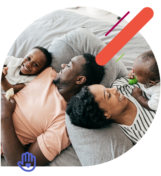 Family of four laying on a bed together and smiling