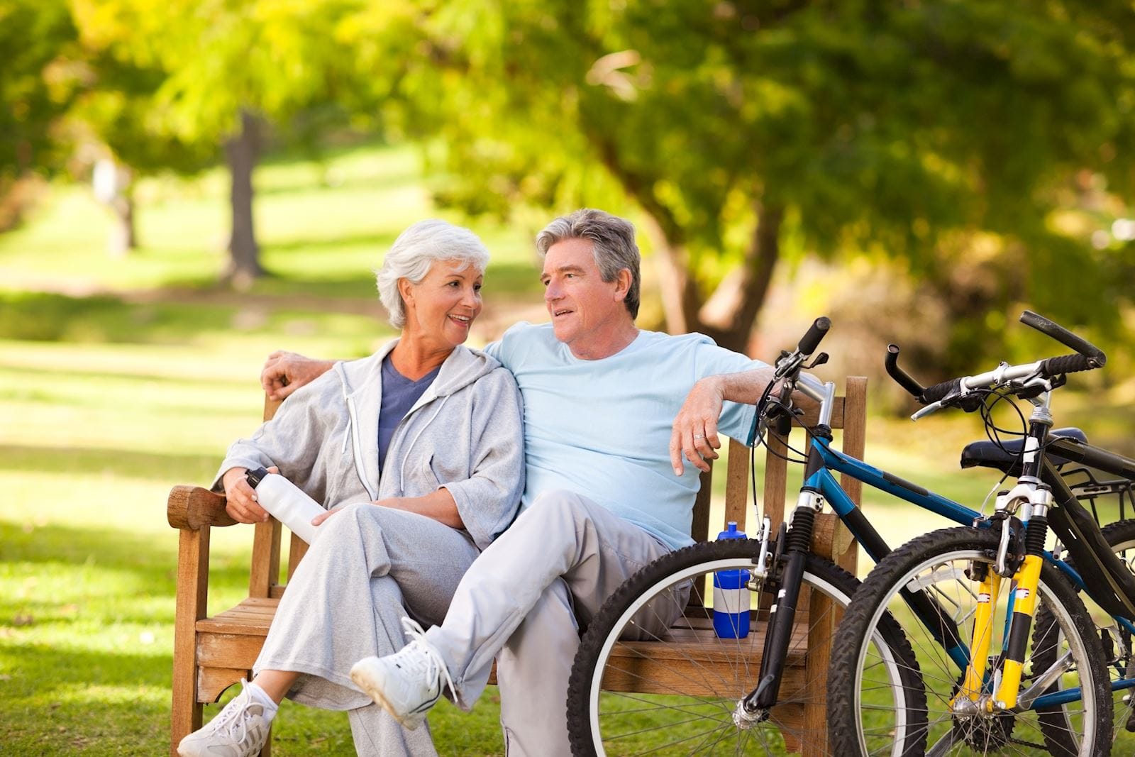 Older couple sitting on park bench next to their bikes